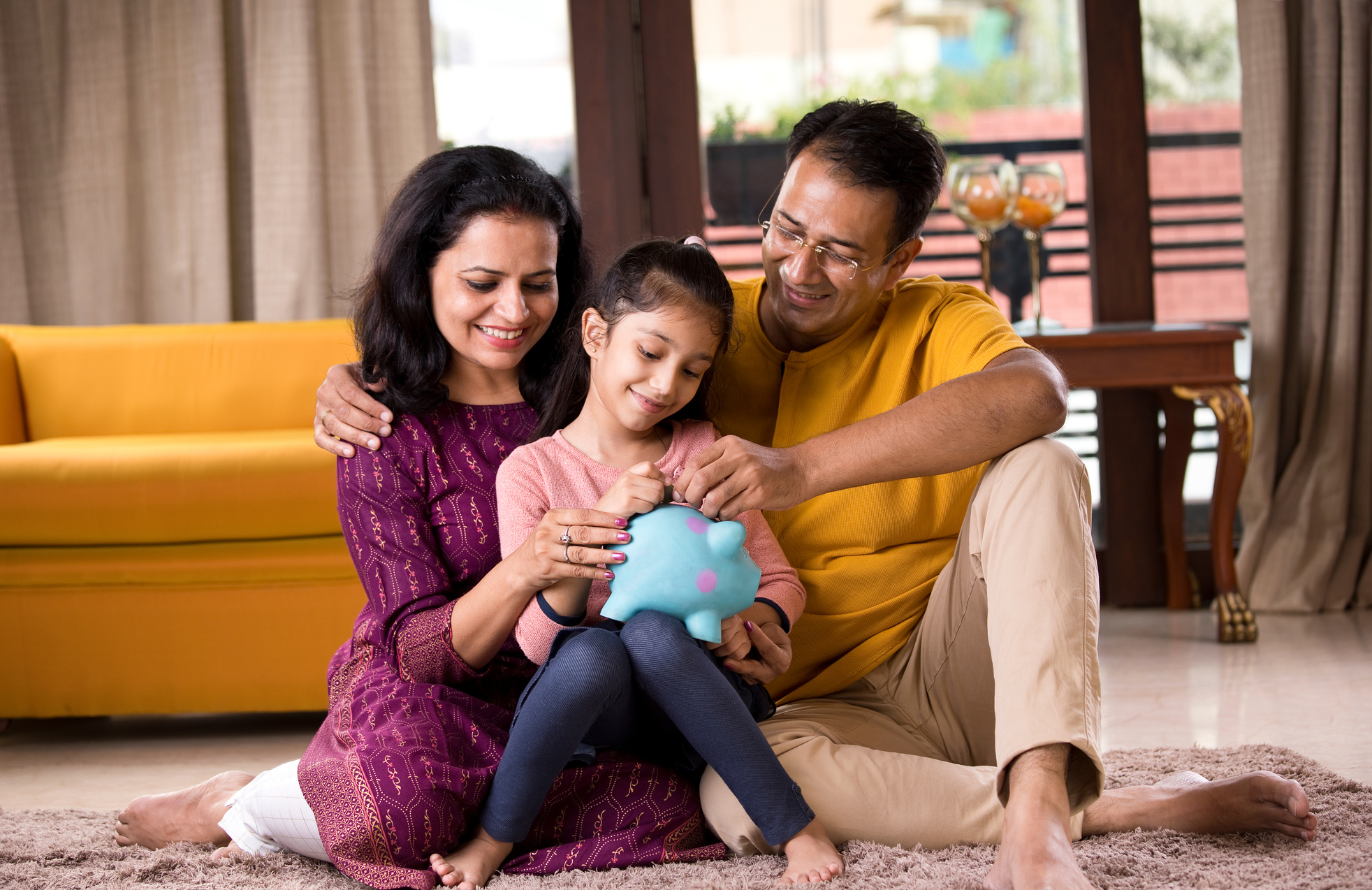 Parents with child saving money in piggy bank
